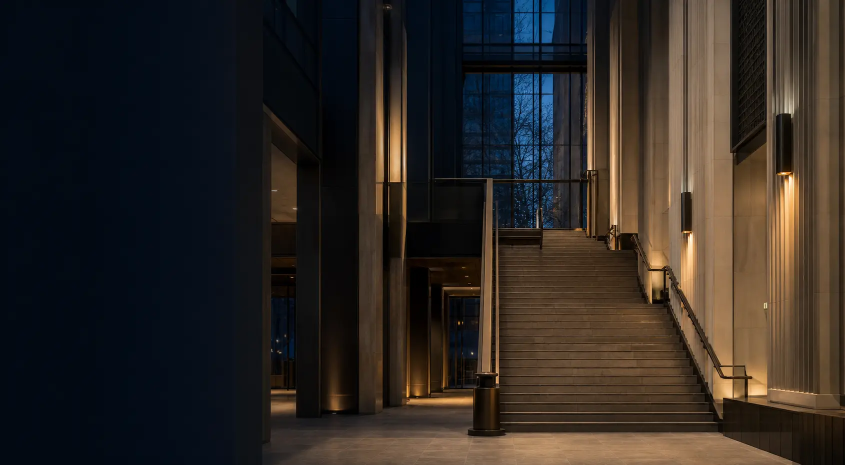 A contemporary institutional interior with stone columns and a broad staircase